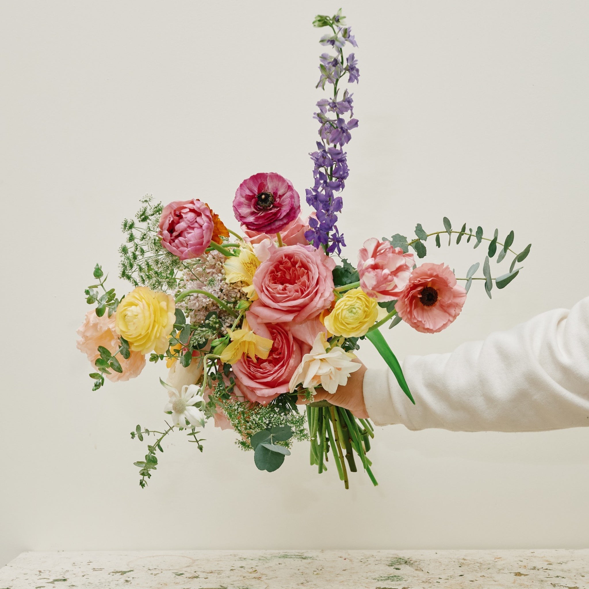 Vibrant floral hand-tied bouquet with roses, ranunculus, larkspur, and eucalyptus - Ora La Casa de Las Flores